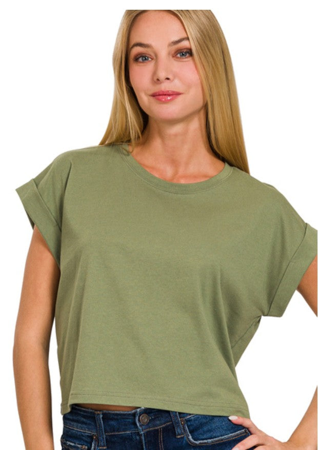 A woman wearing a cropped, short-sleeve t-shirt in olive green, paired with blue jeans, against a plain white background.