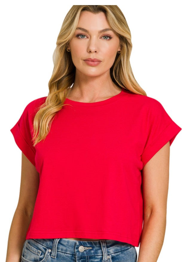 A woman modeling a bright red short-sleeve crop top with a relaxed fit, paired with blue jeans, against a plain white background.