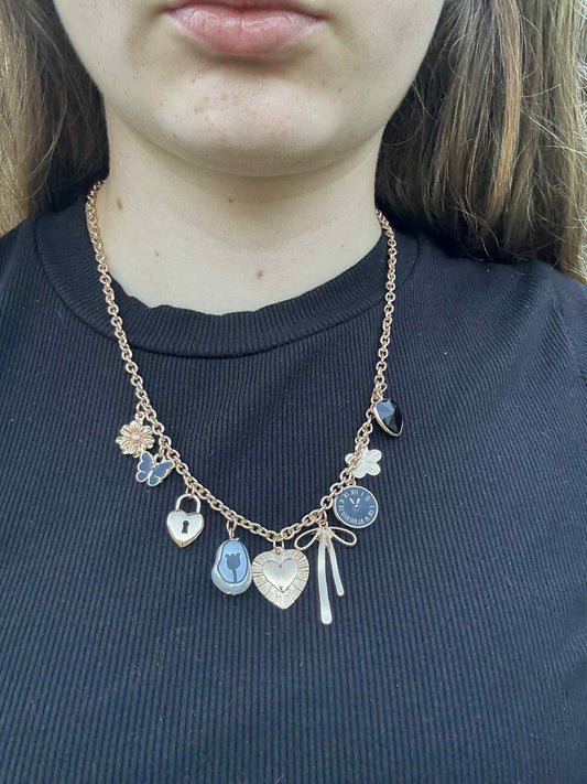Necklace with various charms worn by a person against a dark background
