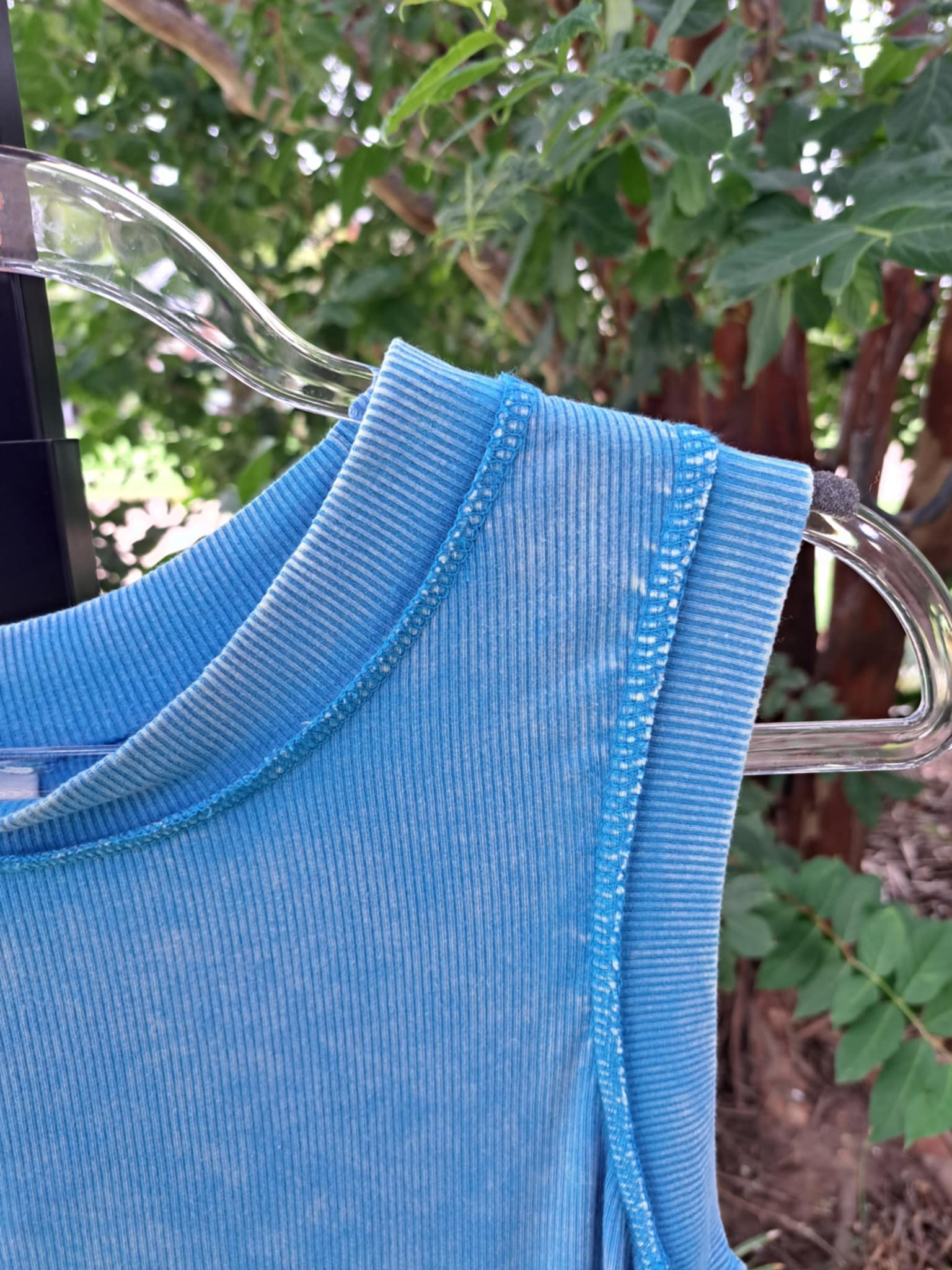 Blue garment on a hanger with a blurred green outdoor background