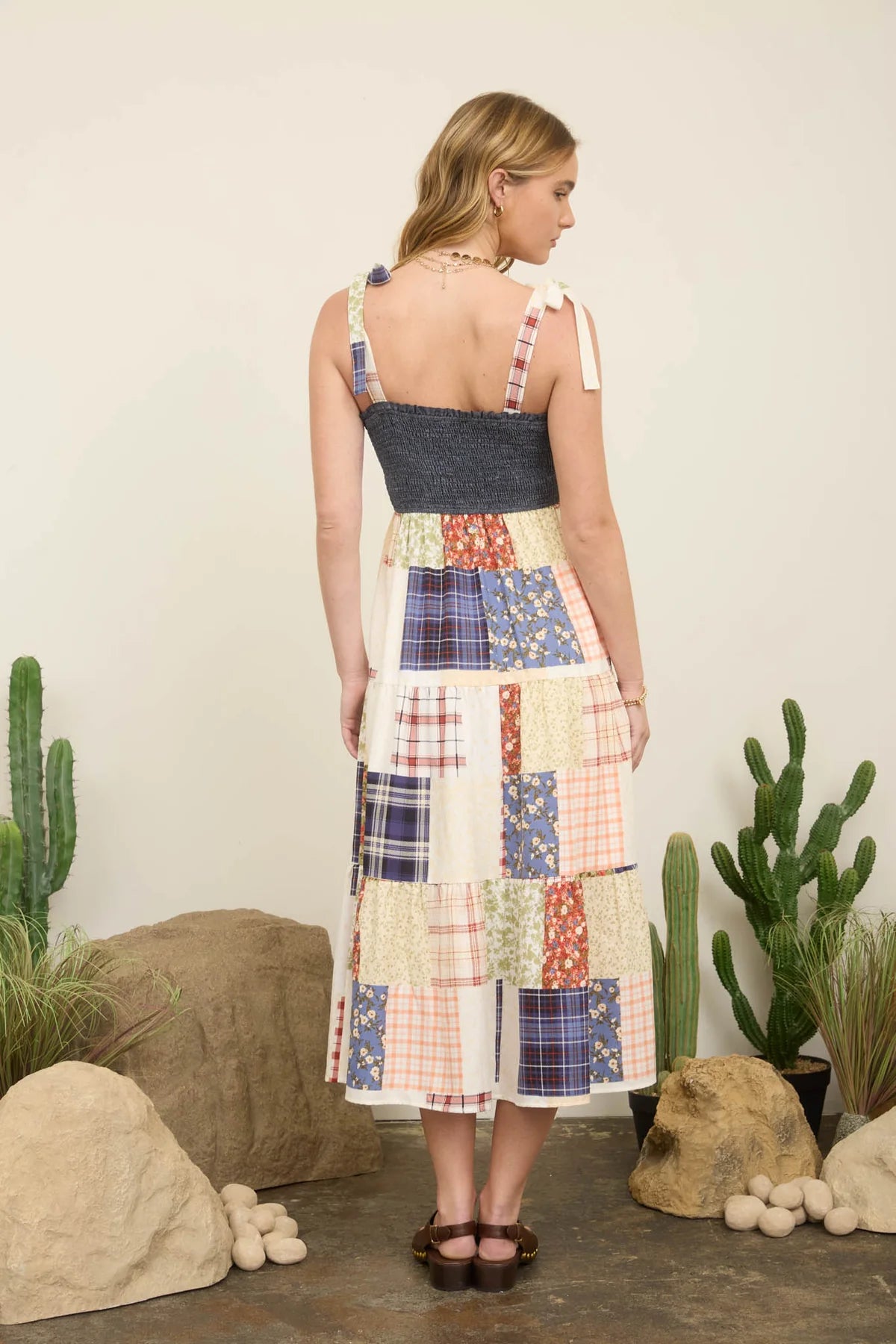Woman wearing a patchwork dress standing in front of cacti.