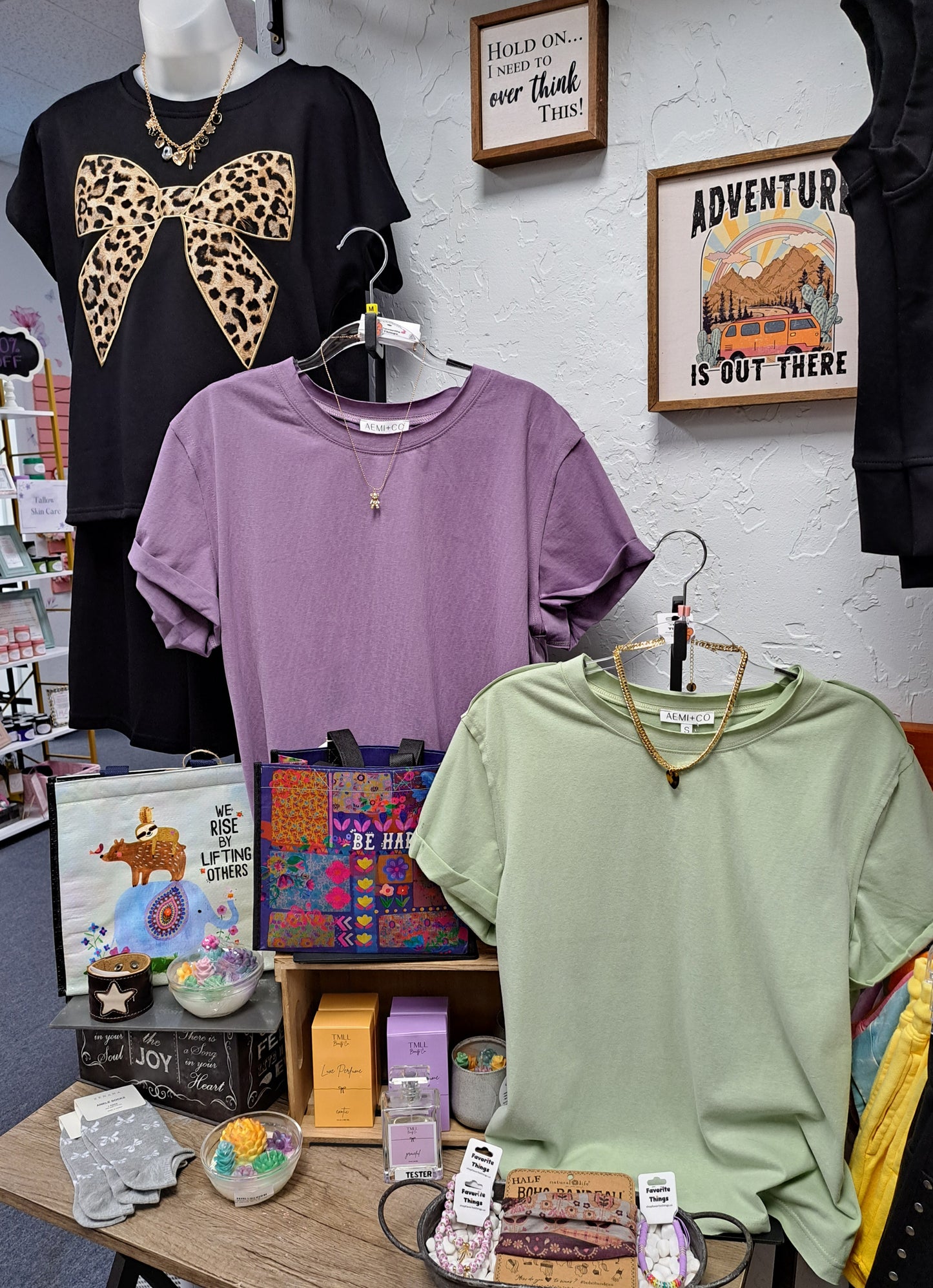 Display of t-shirts and accessories on a table with a white wall background