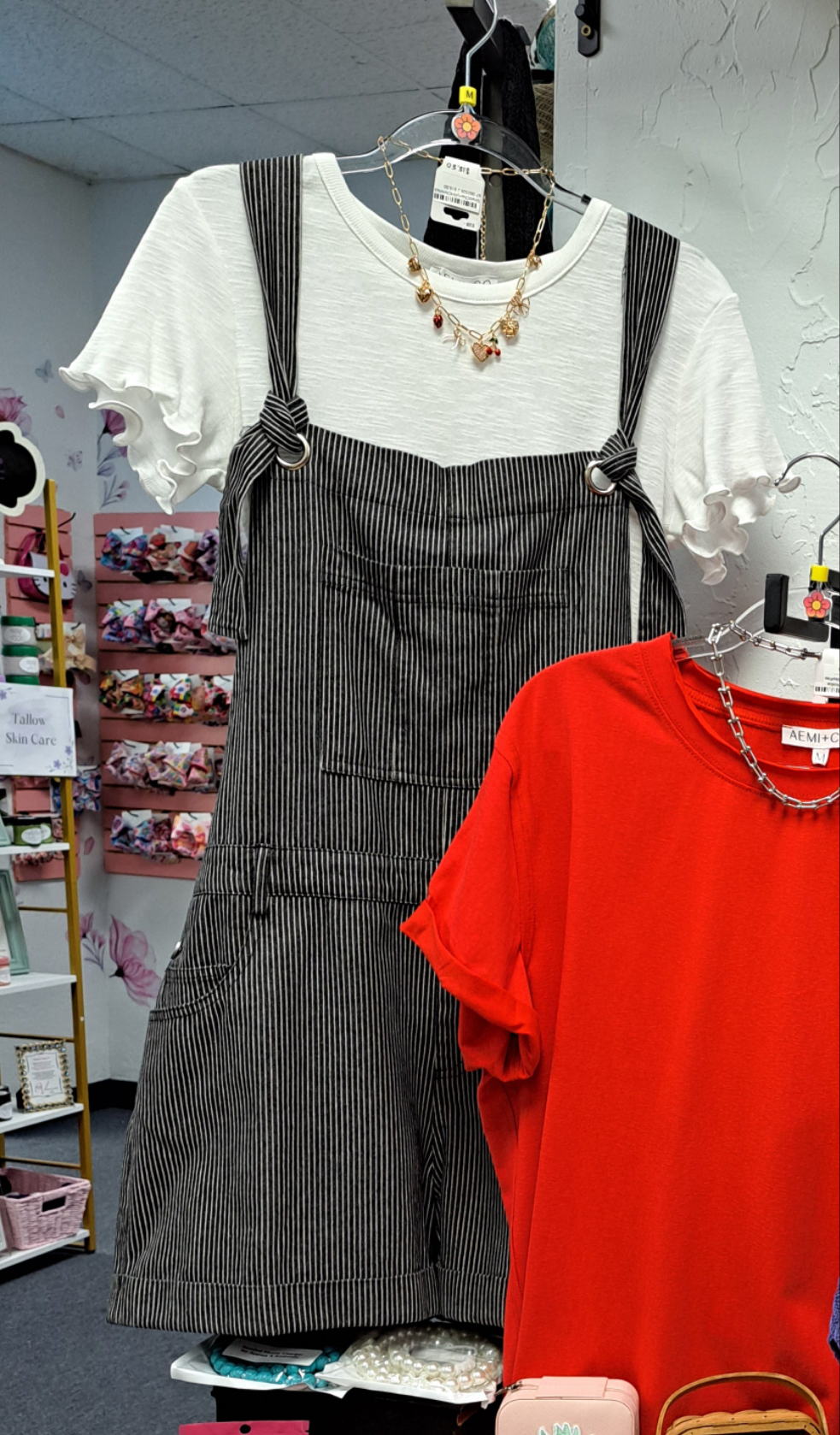 Gray pinstripe dress over a white blouse with a red shirt in a store setting.