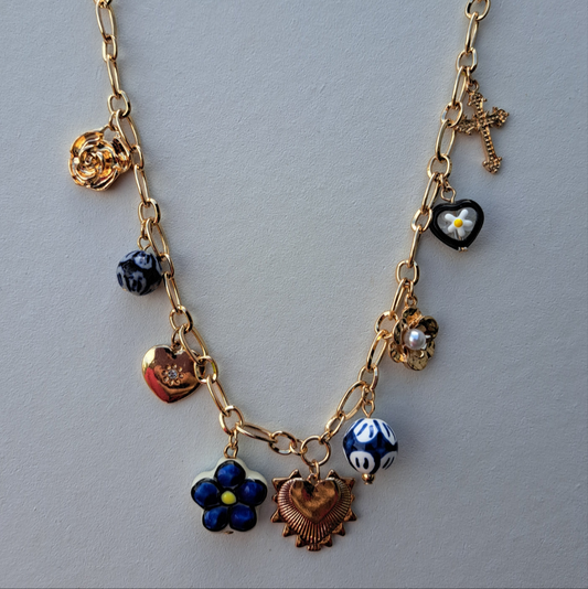 Gold necklace with various charms on a light gray background