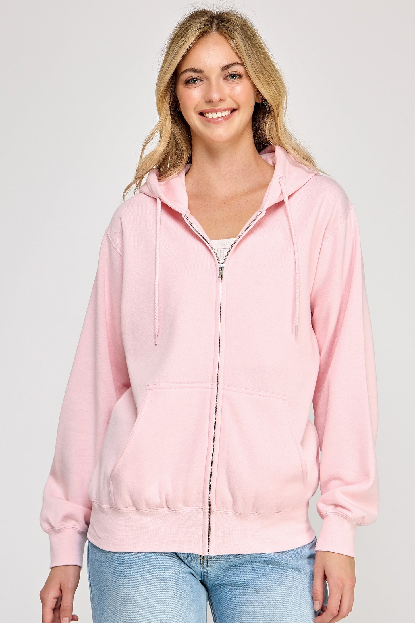 Woman wearing a pink hoodie on a plain background