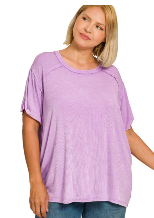 Woman wearing a lavendar washed ribbed boat neck top with reverse stitching