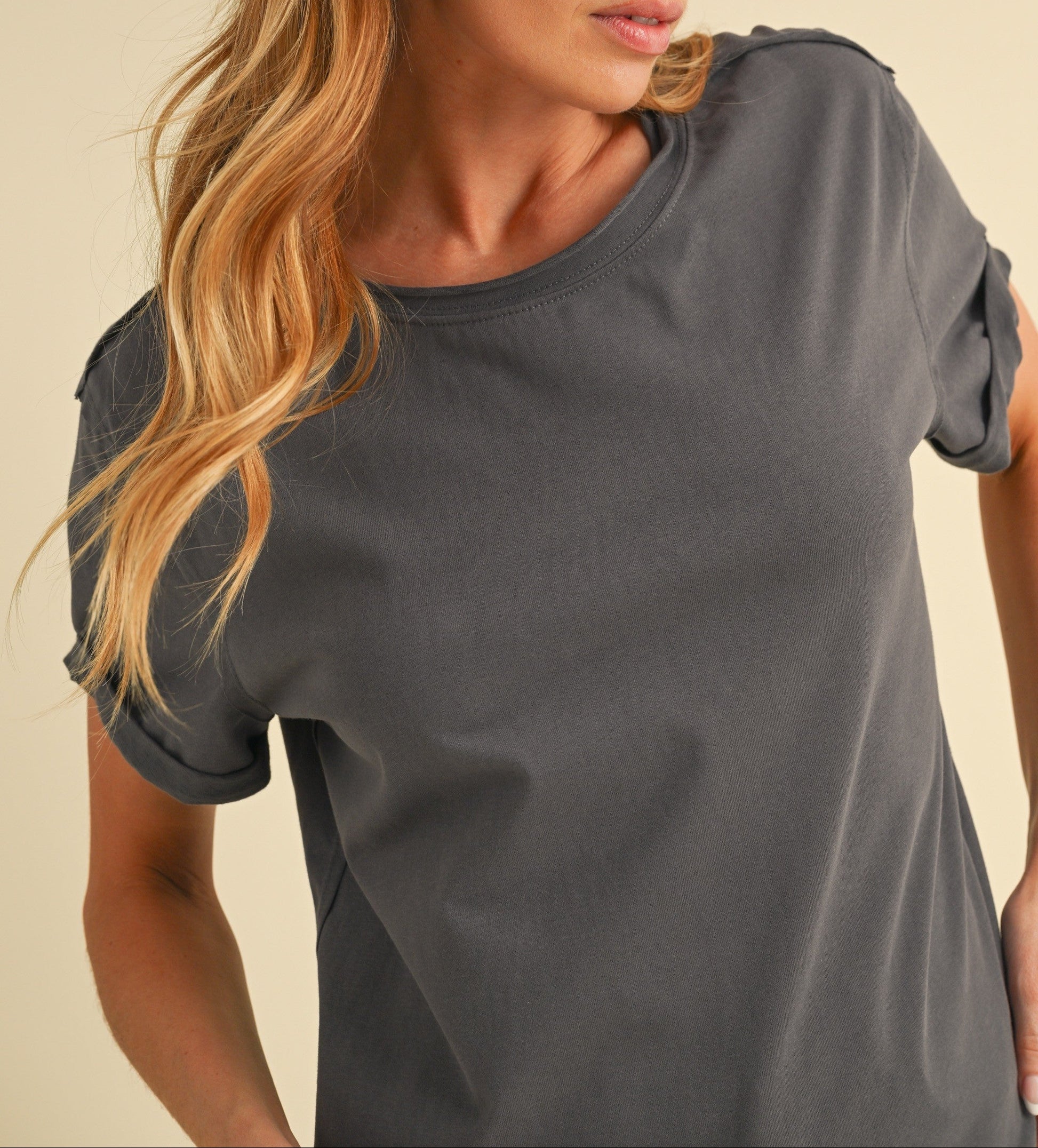 Woman wearing a gray t-shirt against a beige background