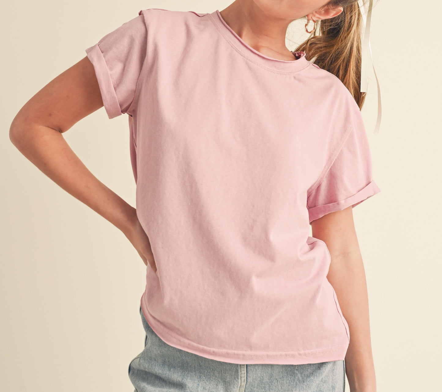 Woman wearing a pink t-shirt and denim skirt on a beige background