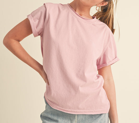 Woman wearing a pink t-shirt and denim skirt on a beige background