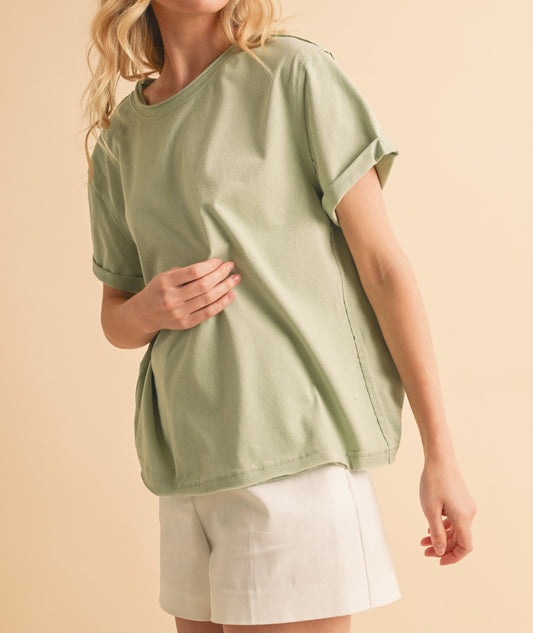 Woman wearing a green oversized t-shirt and white shorts on a beige background