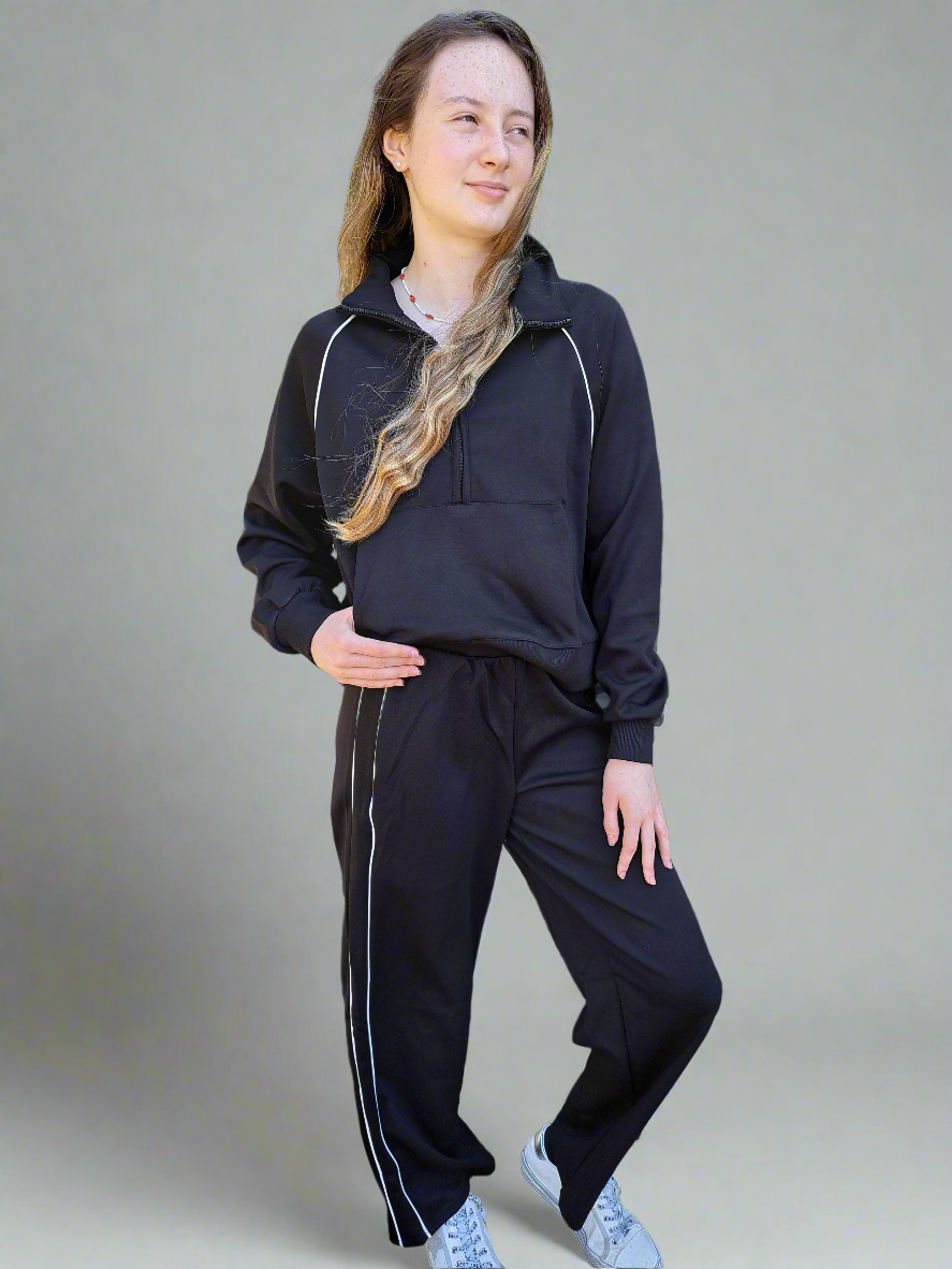 Person wearing a black tracksuit with white stripes on a plain background