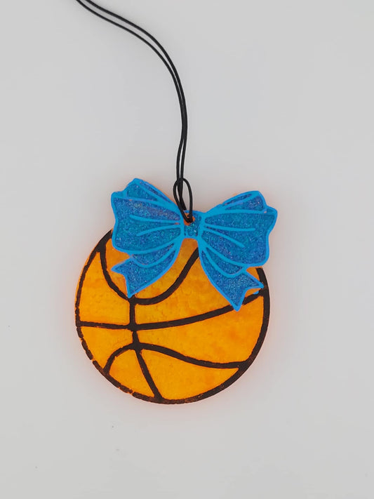 A basketball air freshener with a blue bow and blue trim on a white background