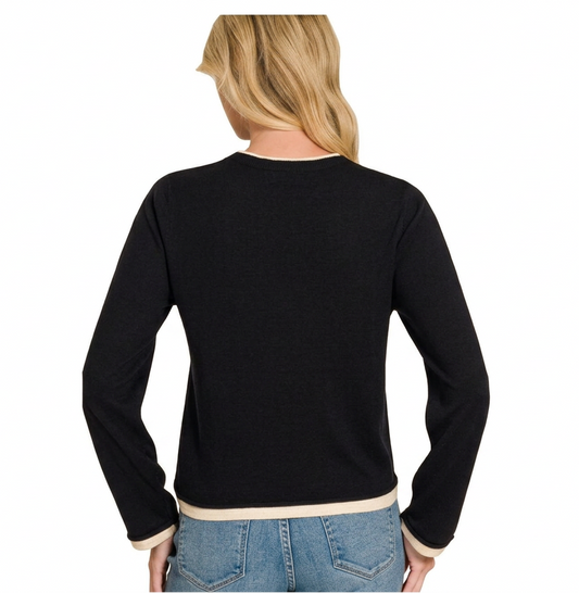 back of woman wearing a black contrast sweater with jeans against a white background