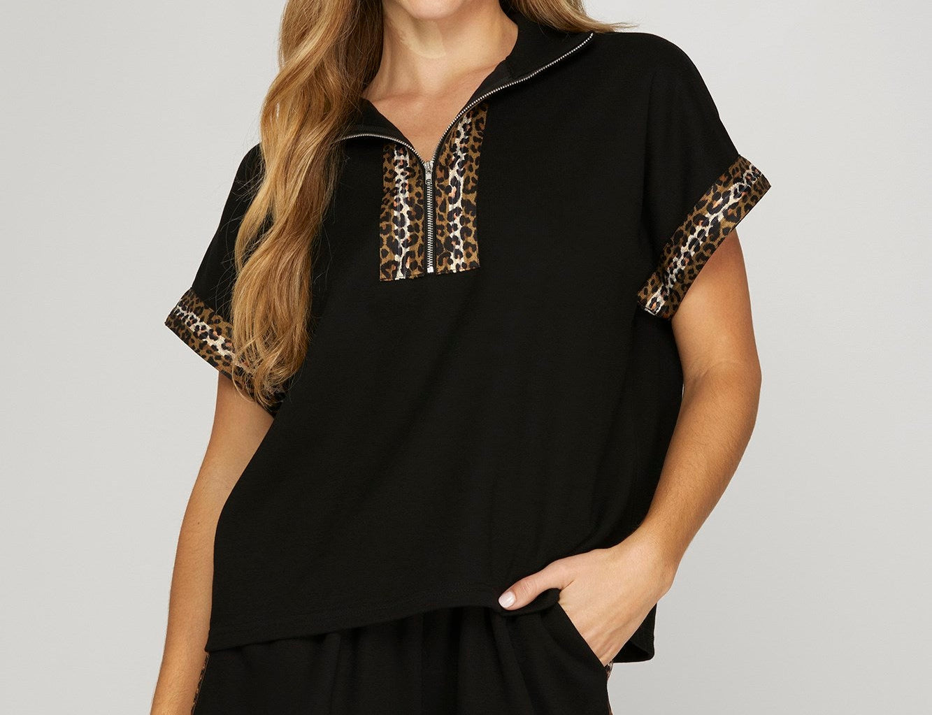 Woman wearing a black top with leopard print stripes. White background