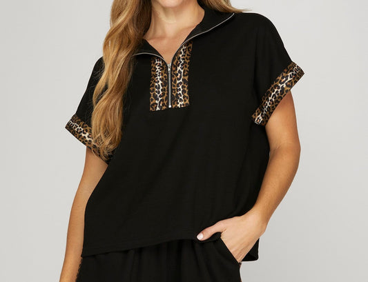 Woman wearing a black top with leopard print stripes. White background