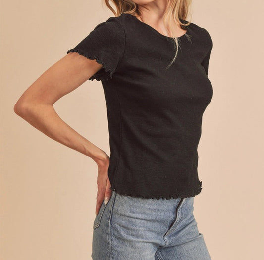 Woman wearing a black top and light blue jeans on a beige background