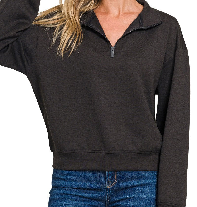 Woman wearing a black quarter-zip sweatshirt with a plain background
