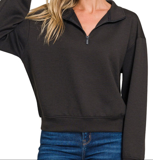 Woman wearing a black quarter-zip sweatshirt with a plain background