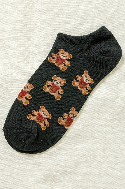 Black ankle sock with teddy bear pattern on a textured beige background
