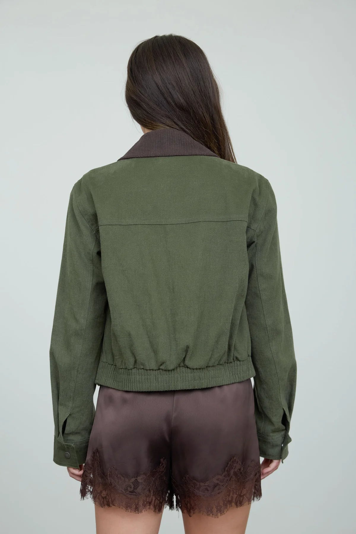 back view of an olive jacket on a woman againsta a neutral background