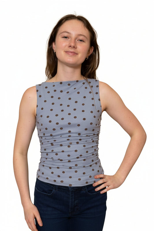 woman wearing blue and brown polka dot top with jeans on a white background