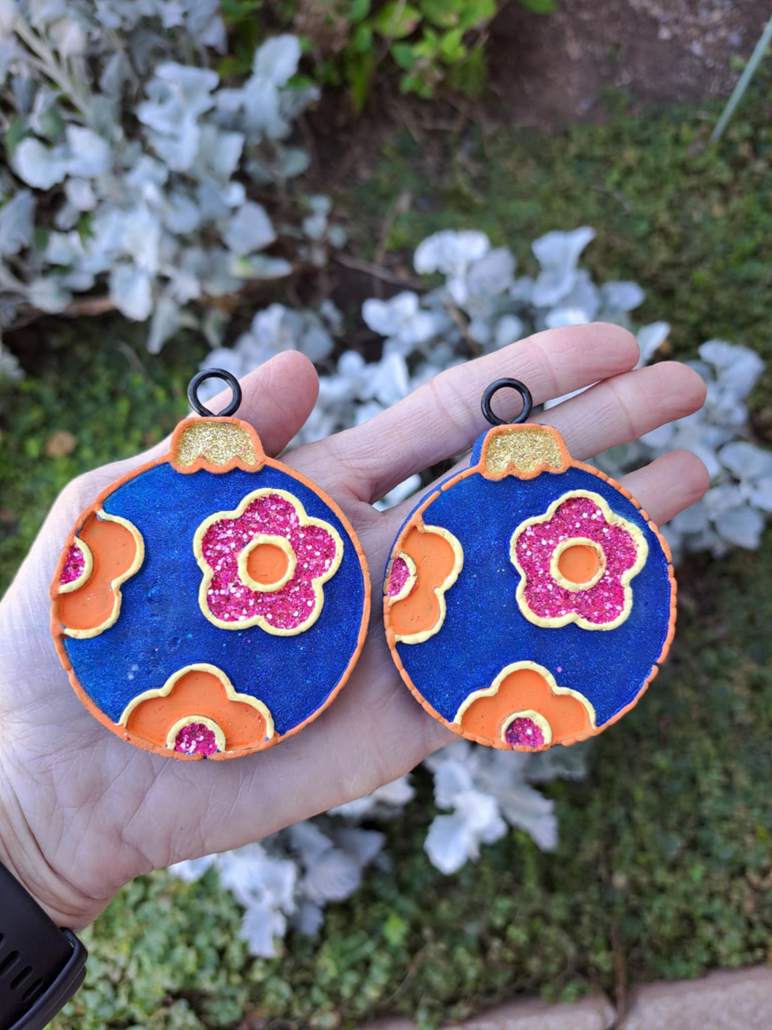 blue bulb vent clips held in hand in front of greenery