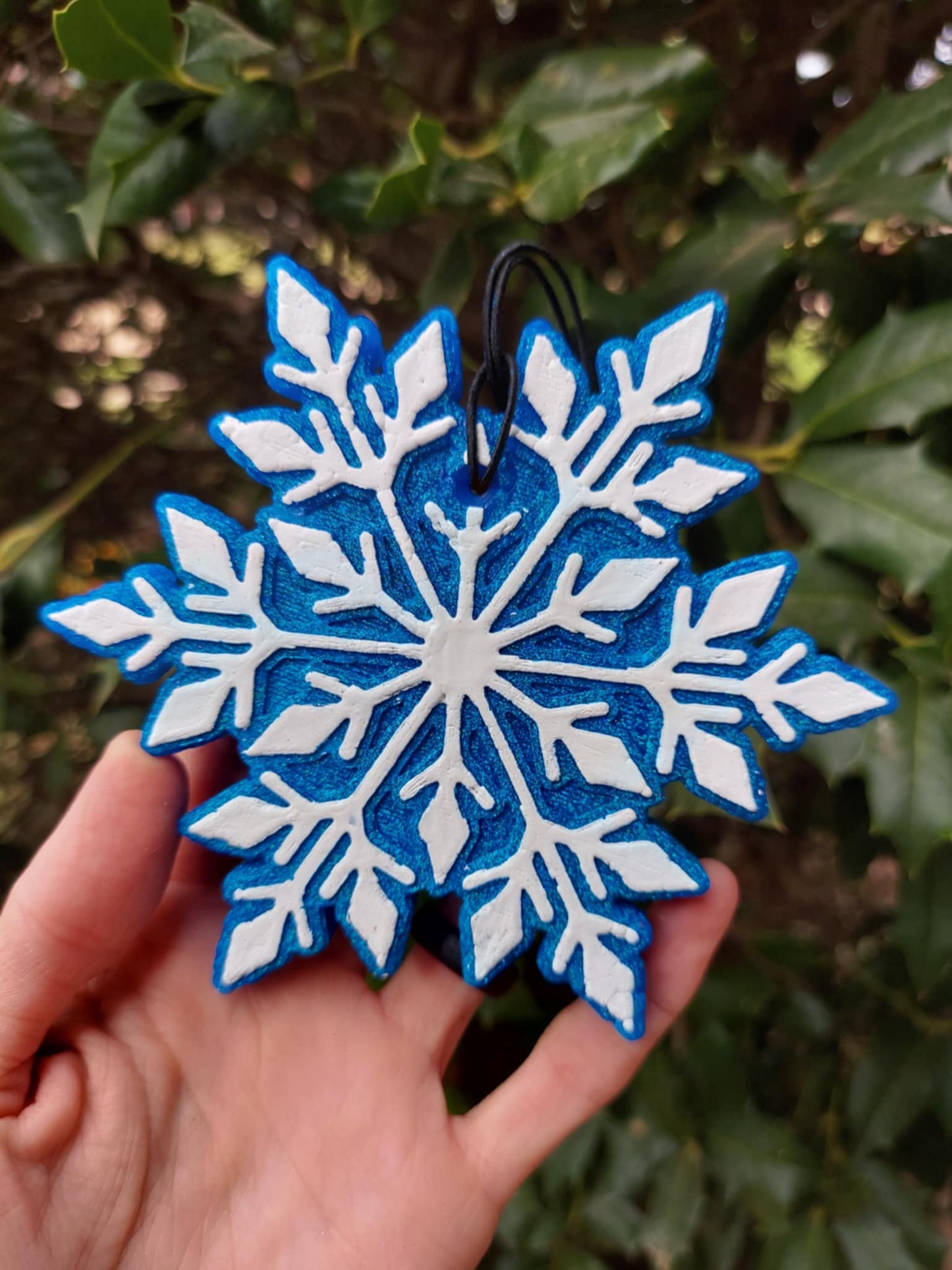 white on blue metallic snowflake air freshener on a background of greenery
