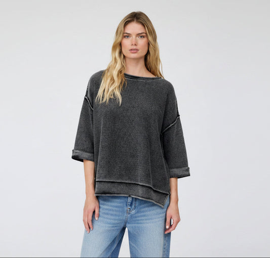 Woman wearing a dark gray oversized sweater and striped shorts on a white background