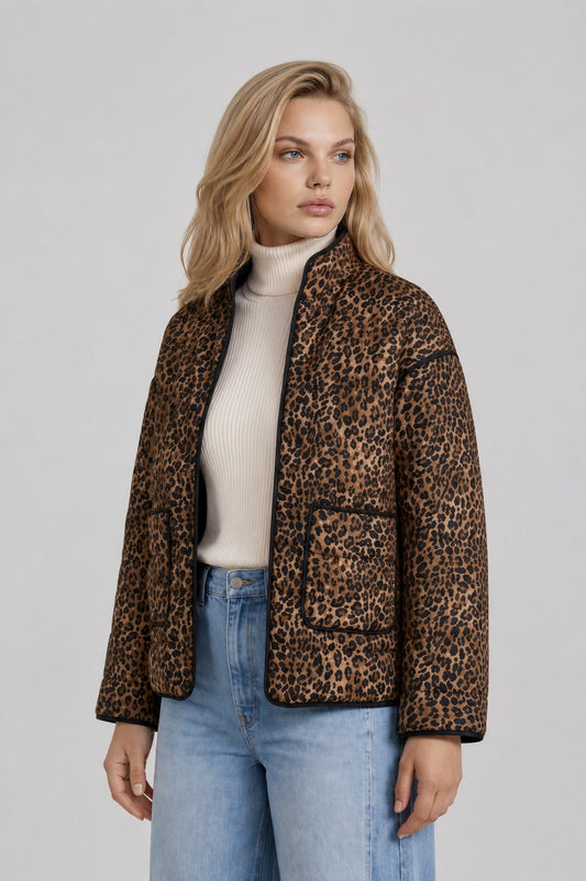 woman wearing leopard print quilted jacket with neutral turtleneck and jeans. Standing in front of a neutral background.