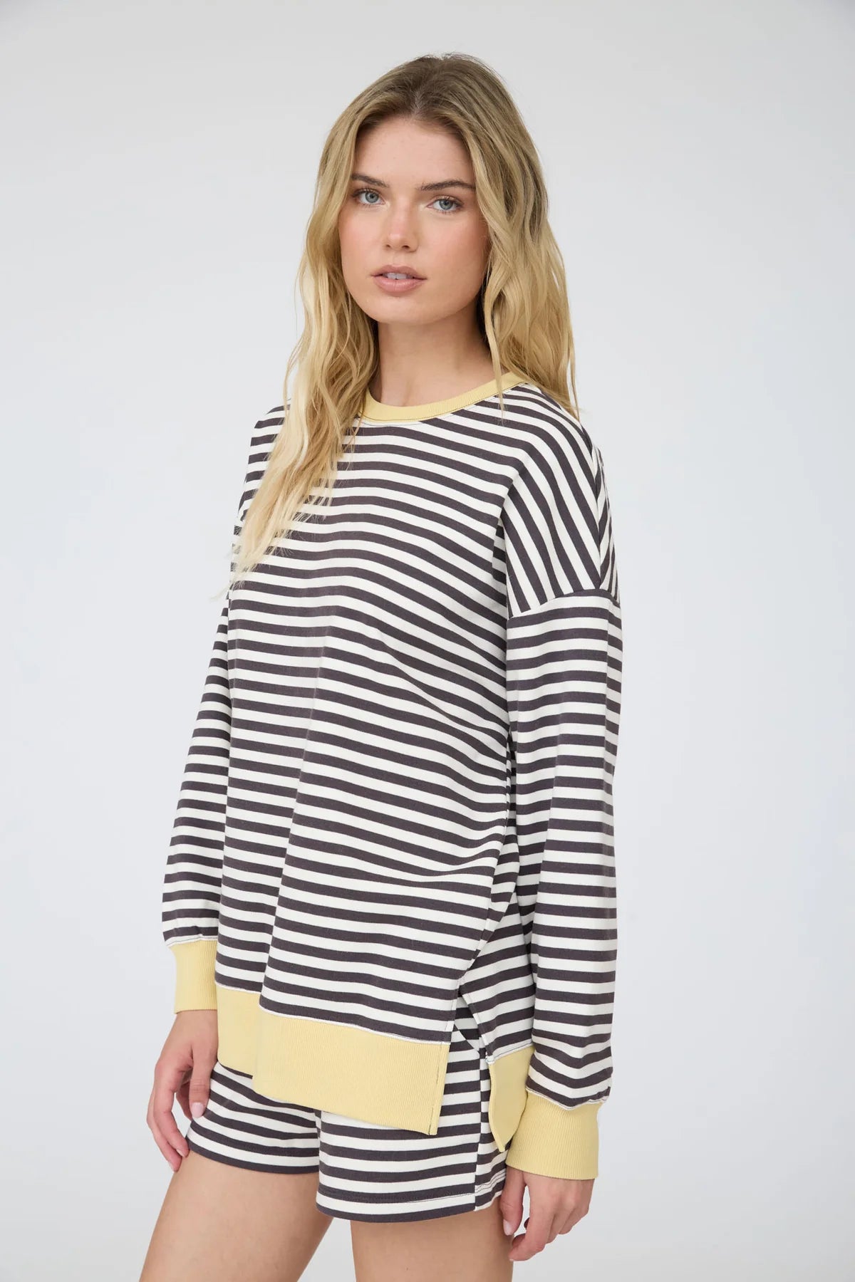 side view of a charcoal striped knit top and shorts on a woman standing against a white background