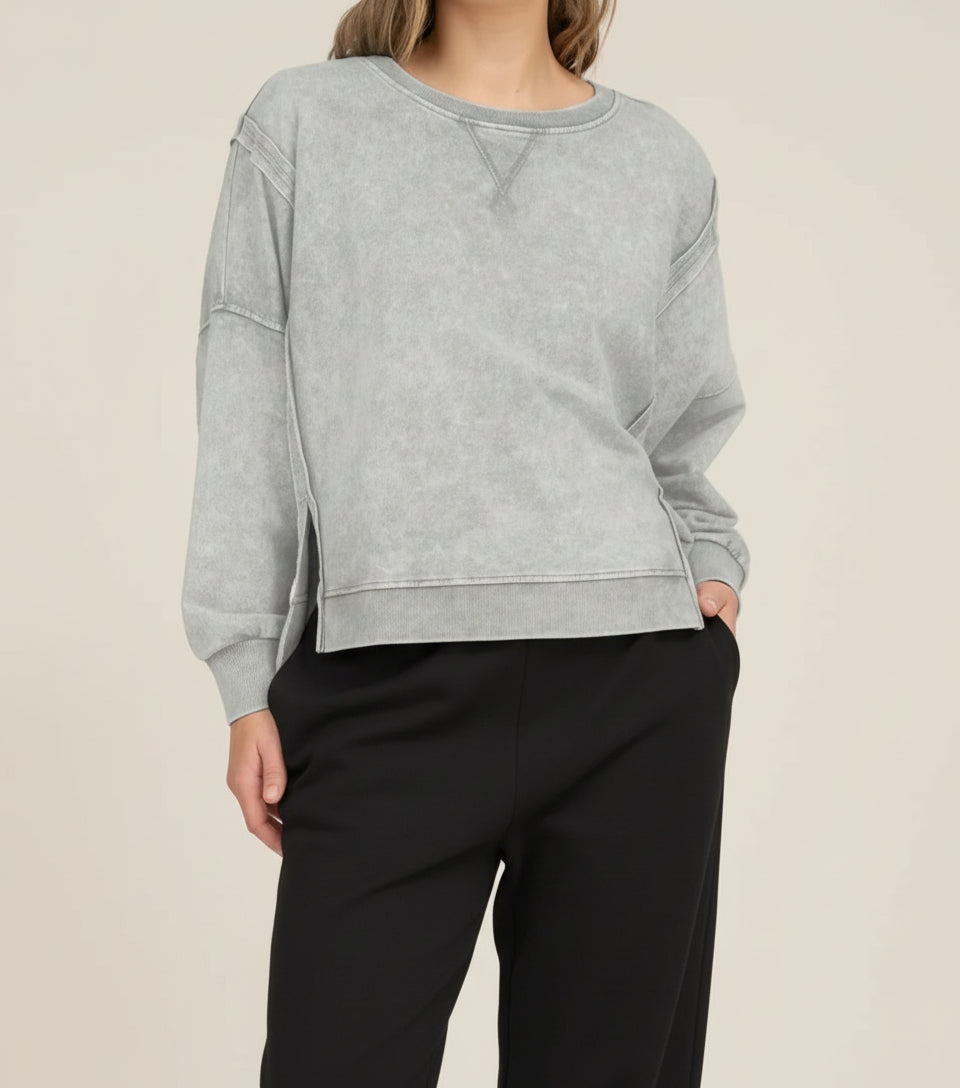 Woman wearing a gray sweatshirt and white pants on a white background