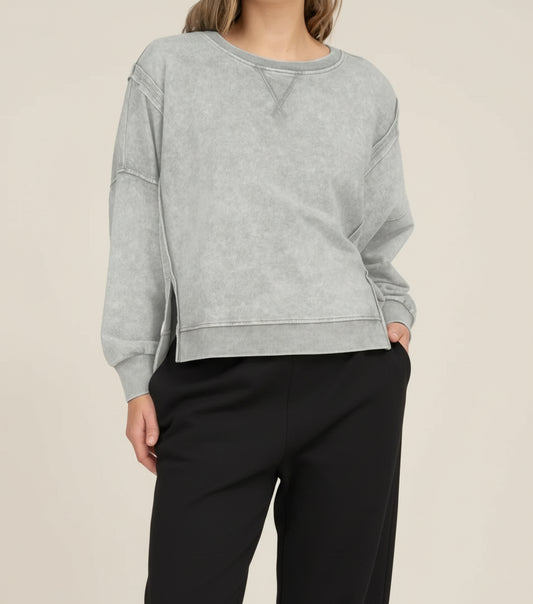 Woman wearing a gray sweatshirt and white pants on a white background