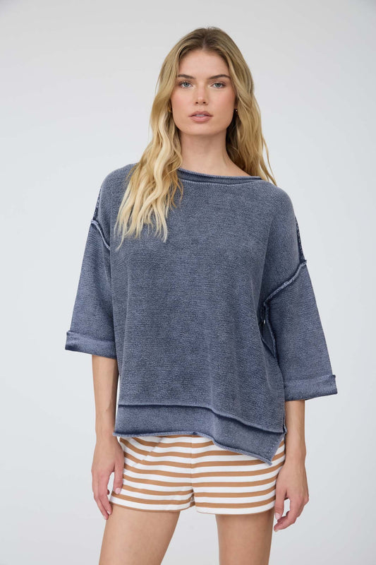 Woman wearing a blue oversized sweater and striped shorts on a white background