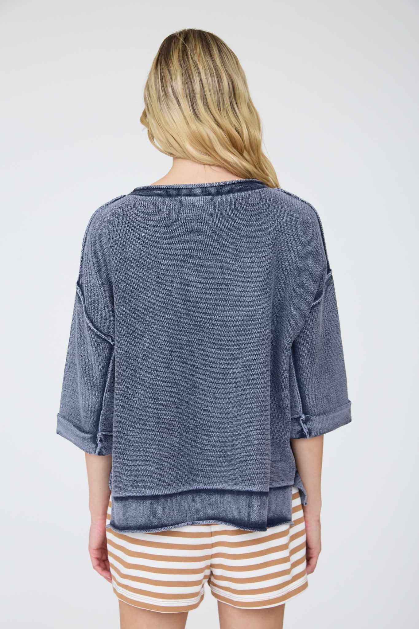 Person wearing a blue sweater and striped shorts on a white background