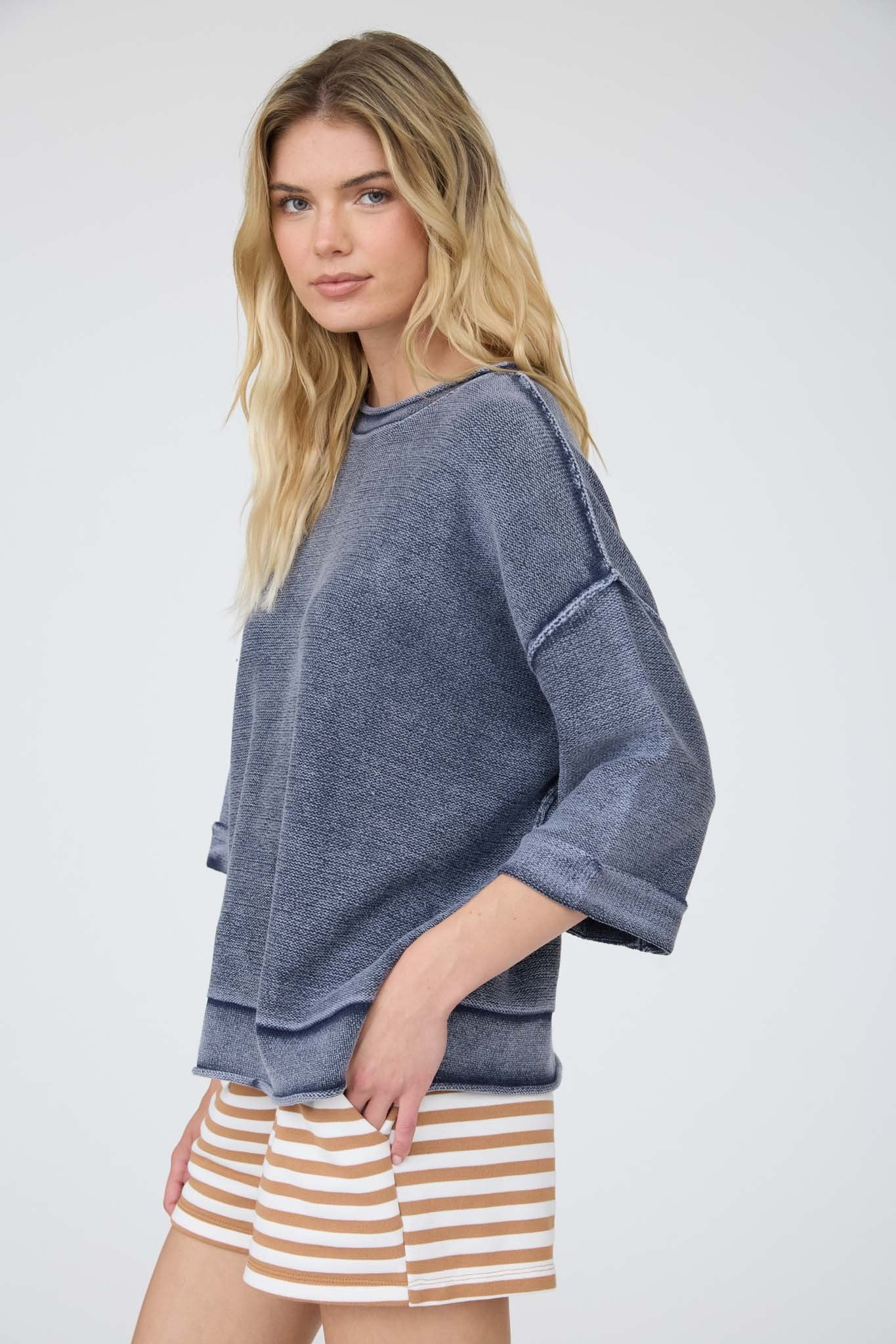 Woman wearing a blue sweater and striped shorts on a white background