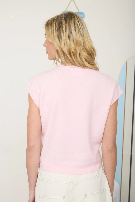 Woman wearing a light pink sweater against a plain background