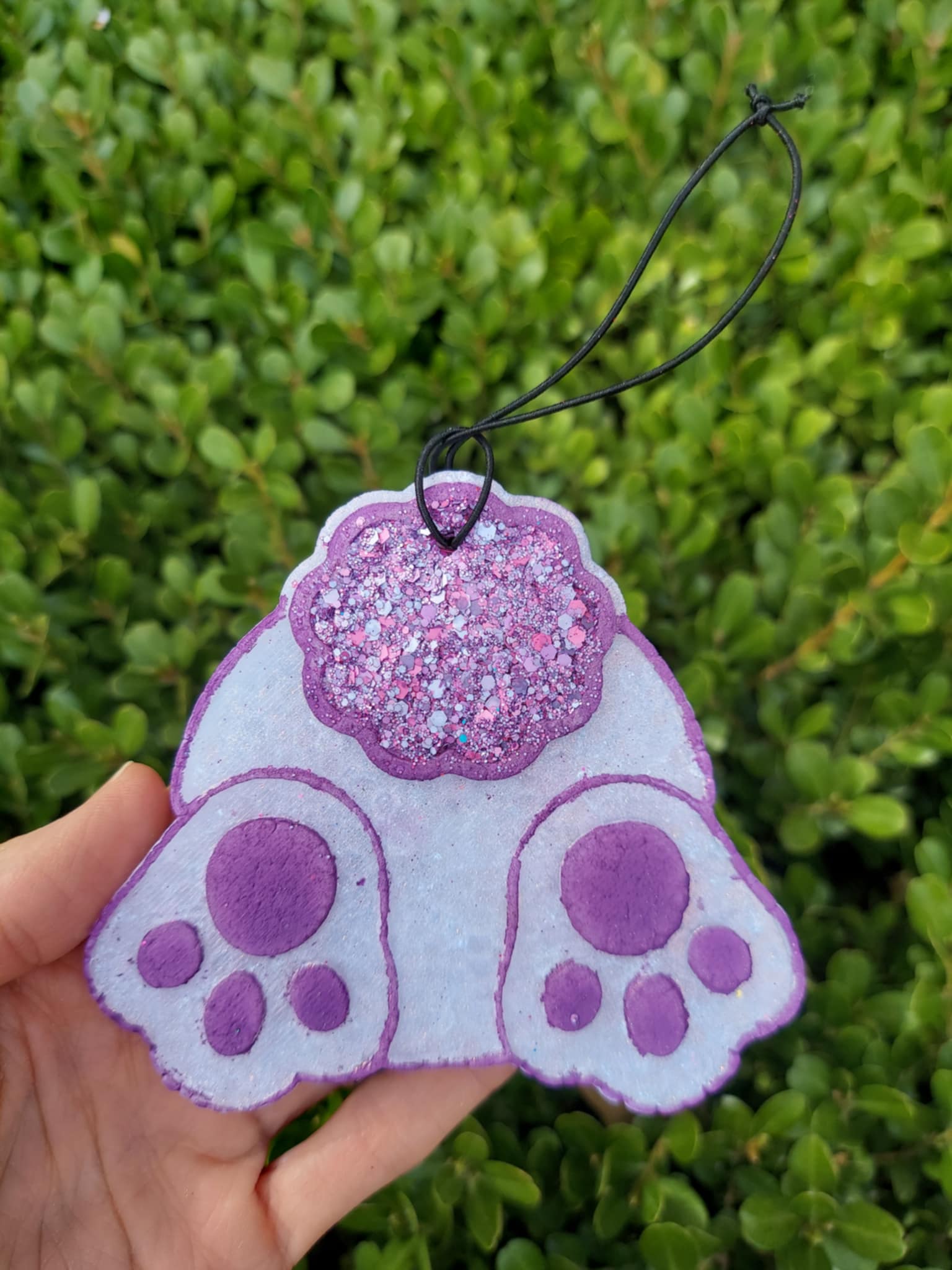 Bunny behind trimmed in purple held against a green leafy background