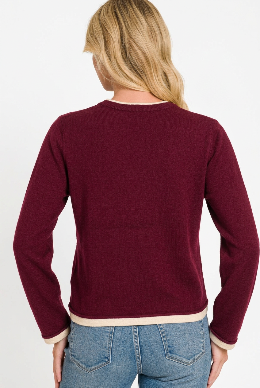 back of woman wearing a burgundy contrast trim sweater and jeans against a white background