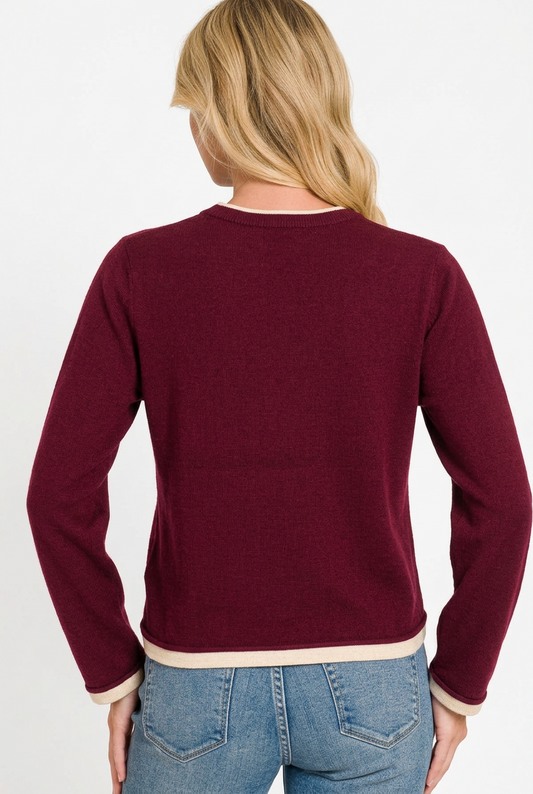back of woman wearing a burgundy contrast trim sweater and jeans against a white background