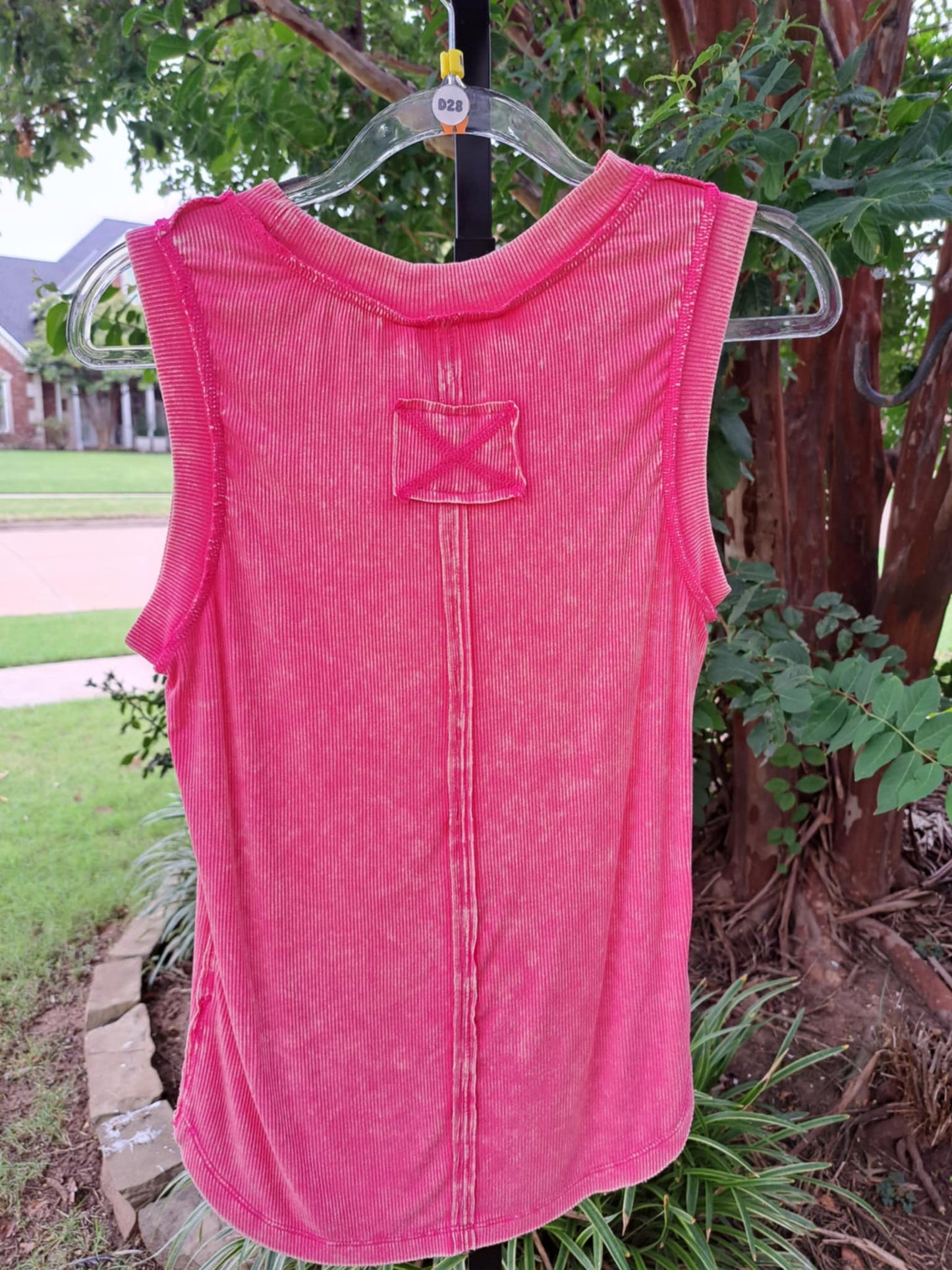 back side of reverse stitched washed pink ribbed tank top with greenery background
