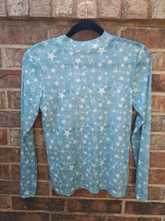 Light blue long-sleeve shirt with star pattern on a hanger against a brick wall.