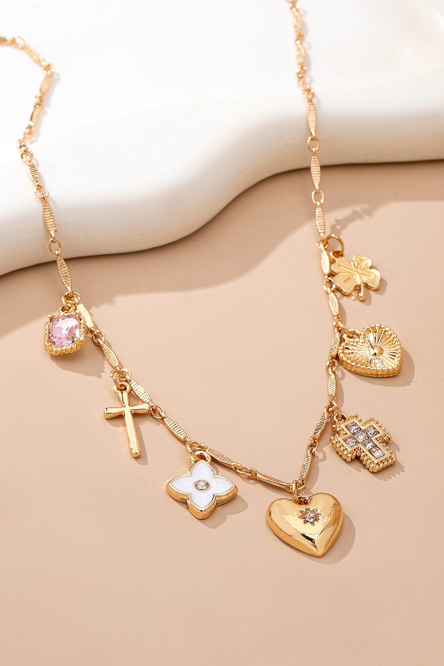 Gold necklace with various charms on a beige background