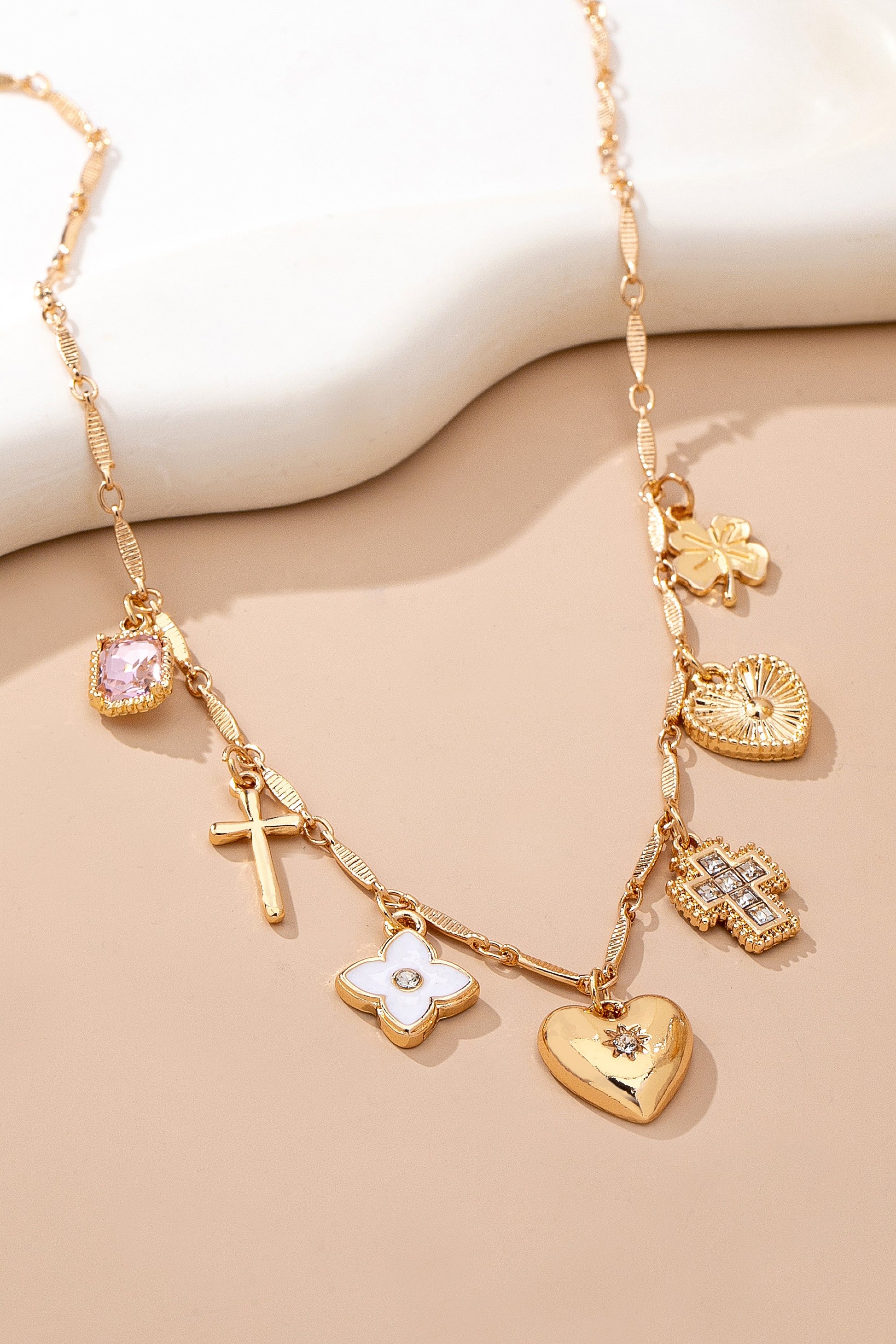 Gold necklace with various charms on a beige background