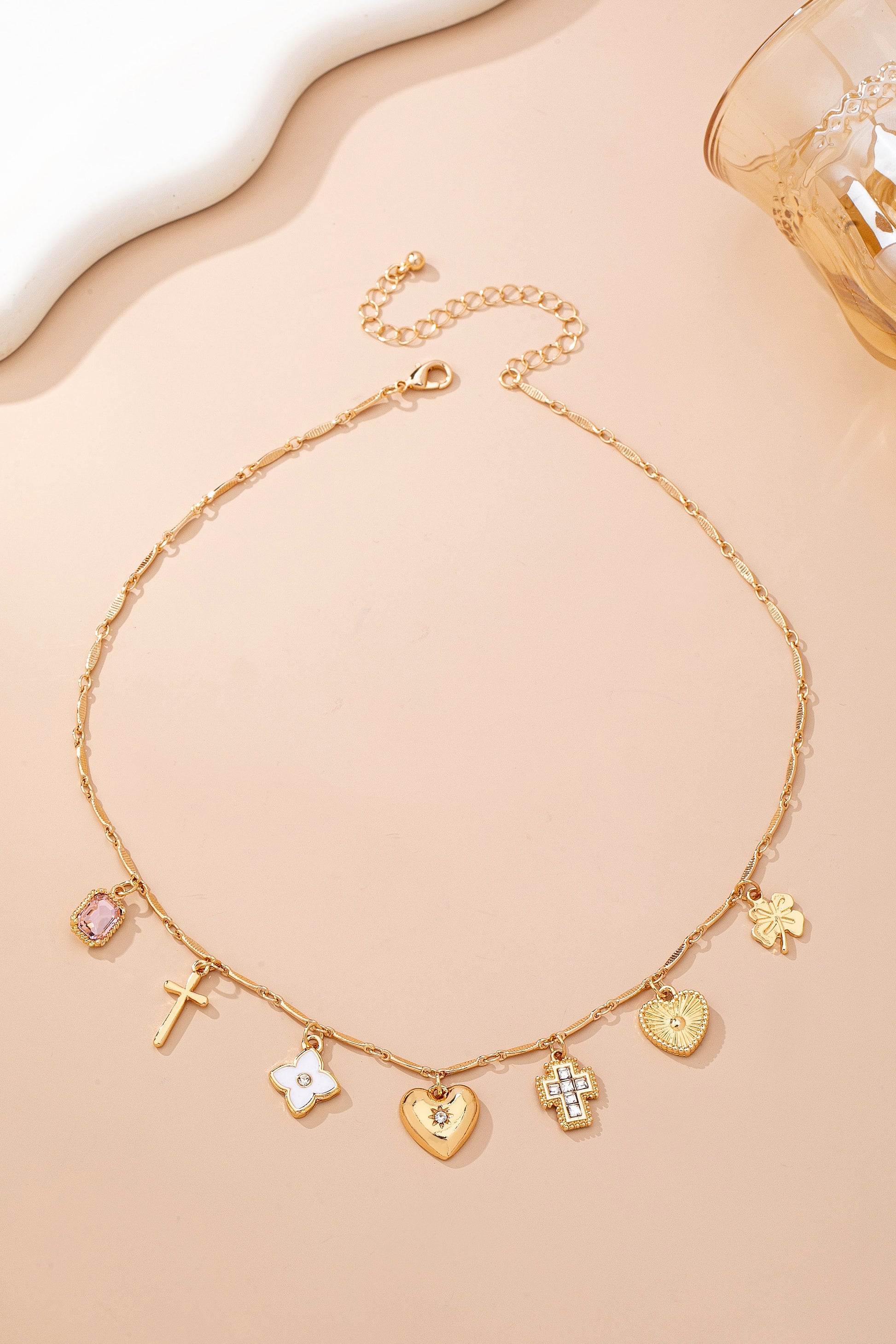 Gold necklace with various charms on a beige background