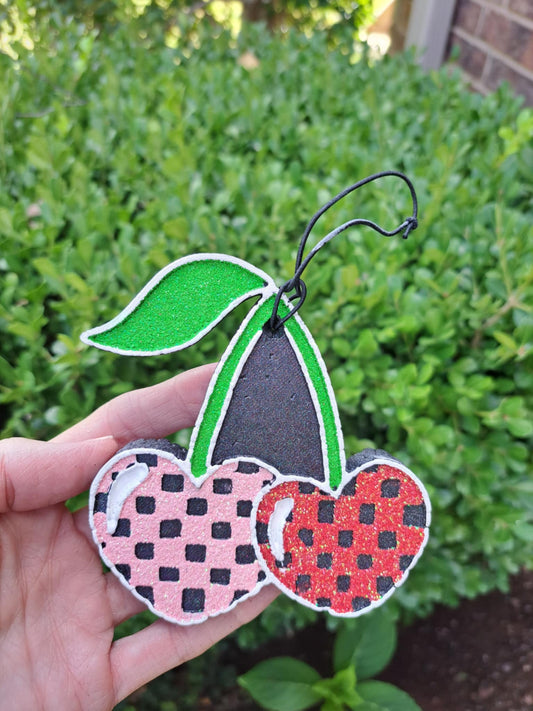 Cherry check freshie pink and red on a green background with a black elastic string