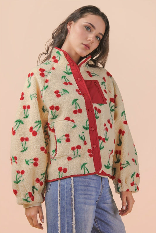 Woman wearing a jacket with cherry pattern on a beige background