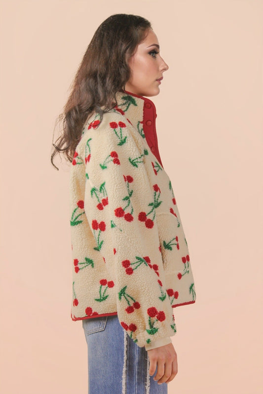 Woman wearing a beige coat with red cherry pattern on a beige background