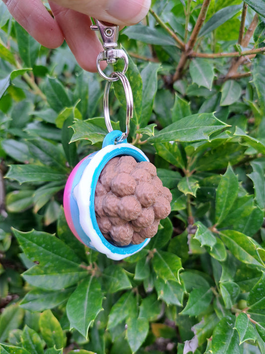Keychain with plastic coco puff cereal in a colorful bowl against a green leafy background