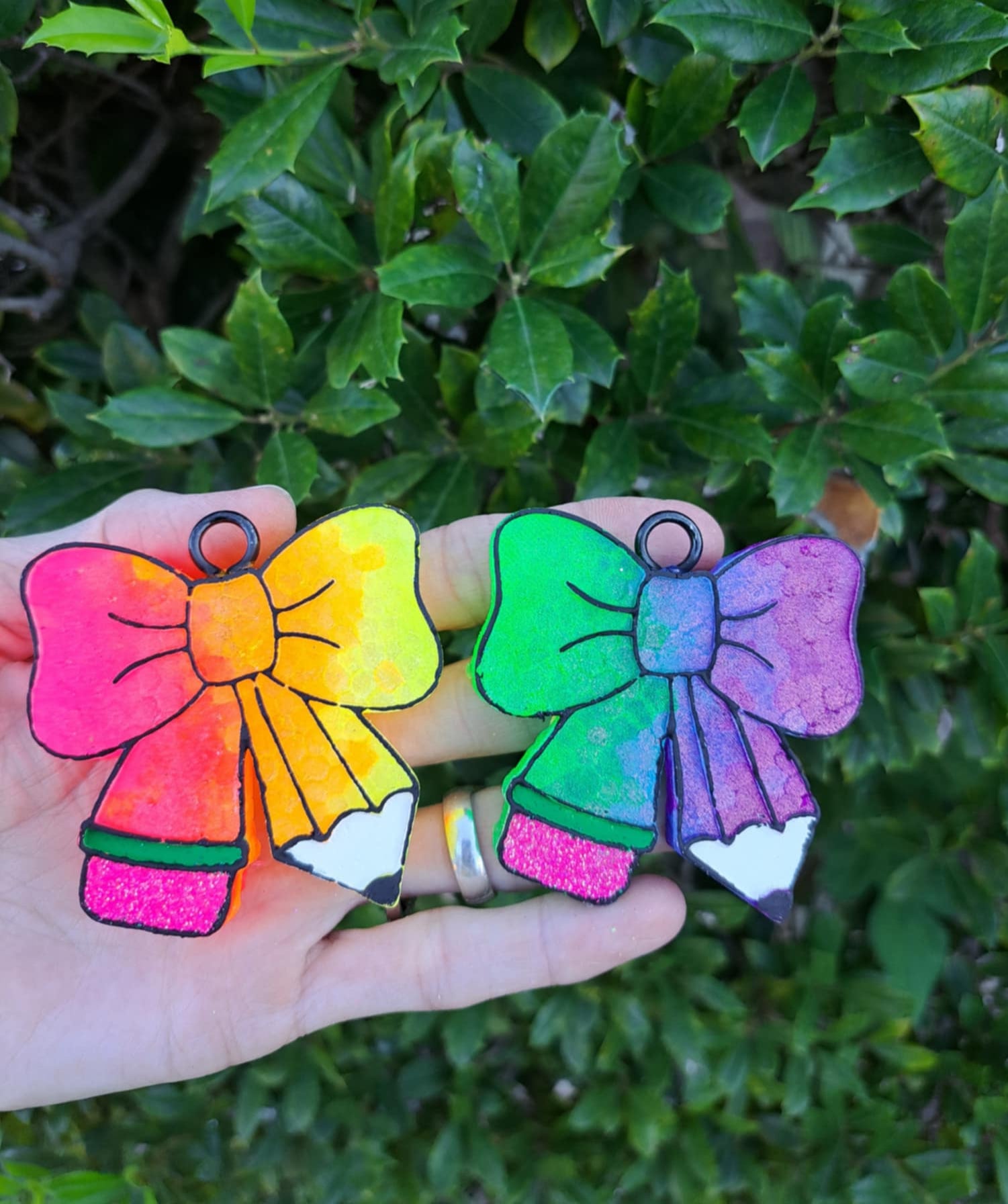 Two colorful bow-shaped freshies held in front of a green leafy background