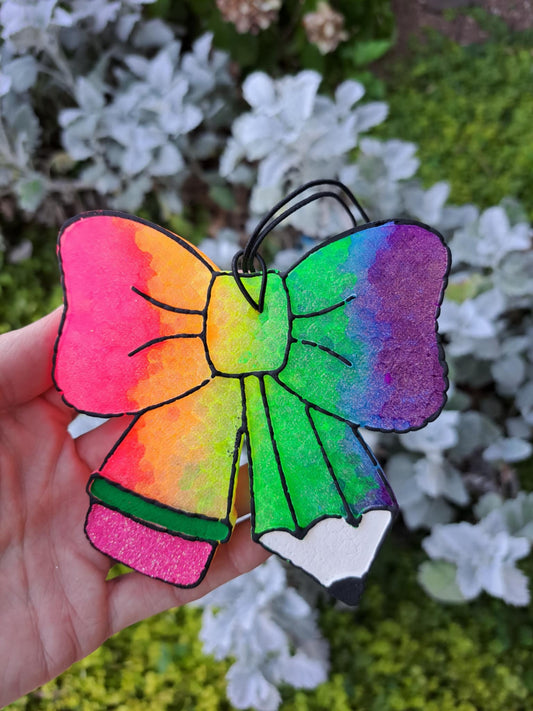 Colorful pencil bow freshie held in front of a natural backround